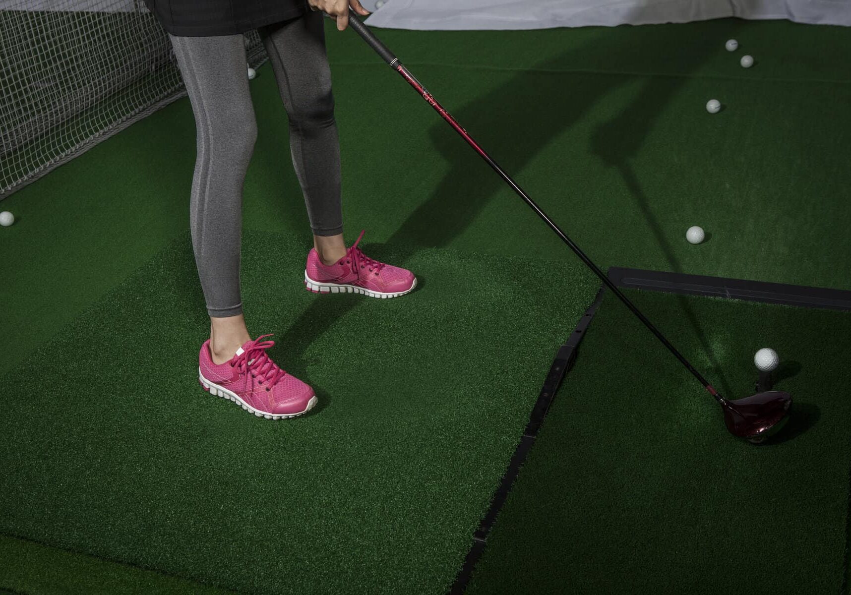 A woman is practicing golf practicing hard by spreading his feet in shoulder width.